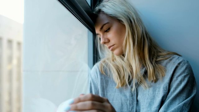 Worried woman sitting near window 4k