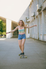 Pretty girl is skateboarding. Smiling girl in striped tank top and shorts rides a skateboard.