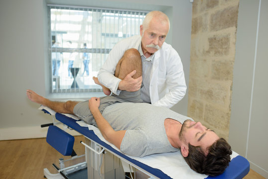 Physiotherapist manipulating man's leg
