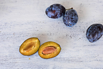 Harvested Fresh blue plums at light wooden background/ Food background/ Flatware