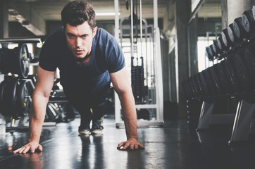 Fototapeta premium sport, fitness, bodybuilding, lifestyle and people concept - man exercising work out and flexing muscles in gym