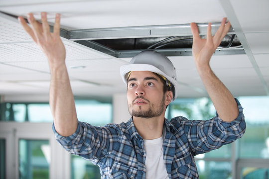 male contractor fitting ceiling panel