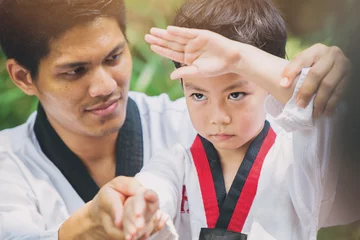 Photo sur Plexiglas Arts martiaux Ceinture noire de maître de taekwondo apprenant à un enfant à combattre la garde