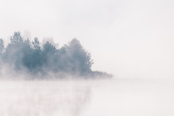 Obraz na płótnie Canvas Beautiful foggy morning. Lake coast. Fog over autumn lake water.