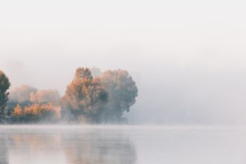 Panorama of calm autumn lake with fog over water and reflections of trees. - 225557083