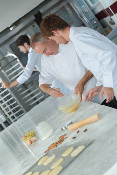 experienced baker teaching male apprentice