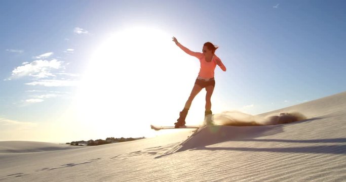 Woman performing a jump while sand boarding 4k