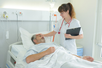nurse taking care of mature patient in hospital room