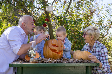 Grandparents and grandchildren carving pumpkins together