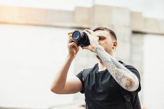 Close up of attractive man making photos of modern building.