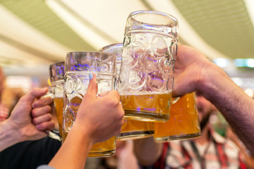 A group of young people Friends toasting with glasses of beer at the Oktoberfest germany Soft focus. Shallow DOF