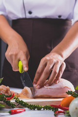 The chef is cutting the chicken meat for cooking