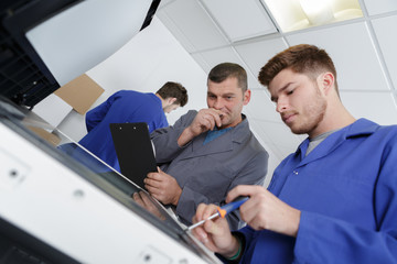 apprentice with screwdriver fixing printer