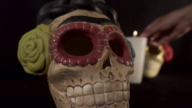 Two skuls with a candle lighting in black background for halloween