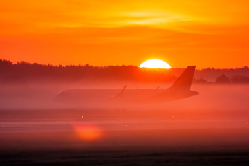 Fototapeta na wymiar Taxiing a passenger airplane in the fog and sunrise