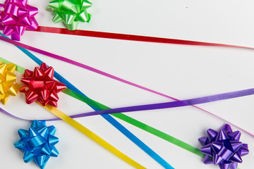 A top view of pink,yellow,red,green,blue and purple gift wrap bows with free lying ribbons  on white background
