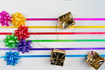 A top view of pink,yellow,red,green,blue and purple gift wrap bows with ribbons and gift boxes on white background