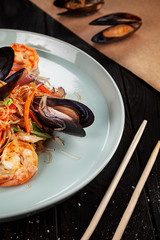 Delicious close up view on Chinese noodles with mussels. Chinese cuisine, dark backround, top view food, copy space for text, selective focus.