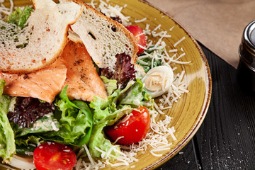 Selective focus on served Caesar salad with Salmon on dark background. Caesar Salad with Salmon, close up view food, copy space for text