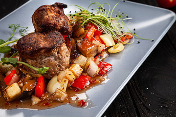 Selective focus on served meat on dark background. Grilled stake with vegetables. Dark background, closeup view, copy space for text.