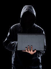 Hacker with hidden face in a hoodie using a laptop on black background