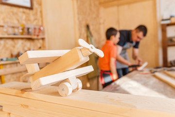 father and little son working together with wood plank at workshop. Carpentry and joinery class...