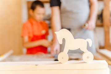 father and little son working together with wood plank at workshop. Carpentry and joinery class concept