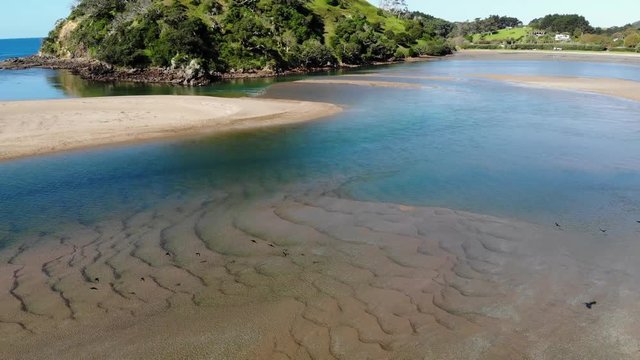 drone shot tracking over estuary towards beach. Pataua mount