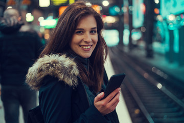 Beautiful young brunette looking at her phone under the bridge