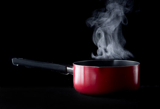Steaming pot over dark background