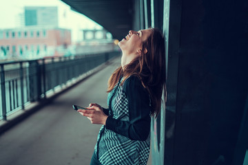 Beautiful young brunette looking at her phone under the bridge