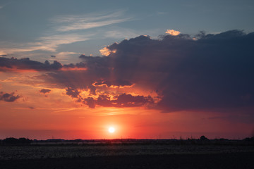 Landscape sunset view with rain and dramatic clouds at the same time. Countryside panorama fields. Braunschweig, Germany