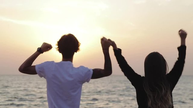 Winning, success , and life goals concept. Young Guy and girl with arms in the air giving thumbs up. Loving couple walking hand in hand. Casual people walking together outdoors