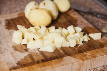 Peeled potatoes diced on cutting board