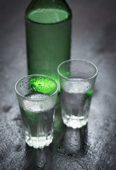 Alcoholic clear distilled korean Soju bottle with shot glass on a wooden background.