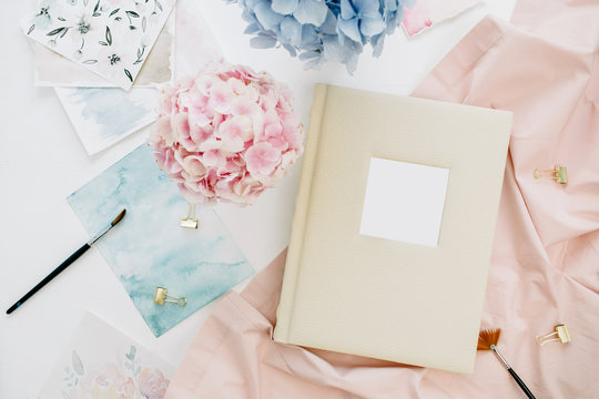Family wedding photo album, pastel colorful hydrangea flower bouquet, peachy blanket, decoration on white background. Flat lay, top view.
