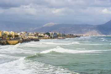 strong waves against the background of the city and mountains in Heraklion, Crete Greece