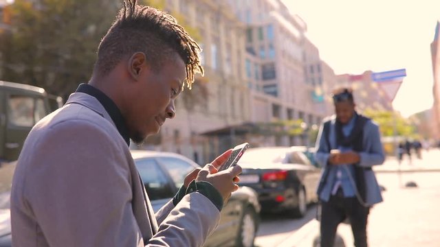 African amrican men using mobile phone app in city texting or browsing