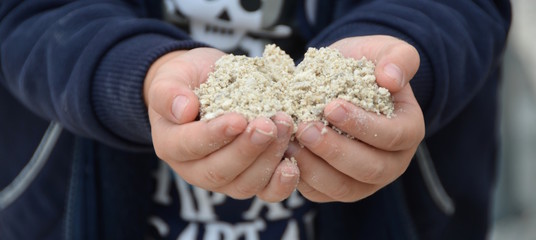 Kleines Kind hält Sand in seinen Händen