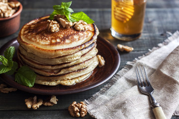 On the table there is a dish with pancakes, honey and nuts.