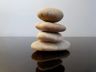 A stack of zen stones on a black table against grey background. Concept of Harmony, Balance and Meditation, Spa, relax