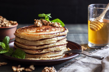 On the table there is a dish with pancakes, honey and nuts.