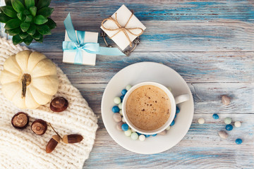 A cup of coffee and colored candies, jewelry boxes, a bracelet with silver charms, succulent and a white decorative pumpkin. Holiday gift with a note.