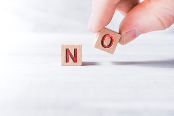 The Word No Formed By Wooden Blocks And Arranged By Male Fingers On A White Table