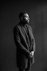 Attractive man in coat on dark background. Professional photo studio. Fashion portrait of young man...