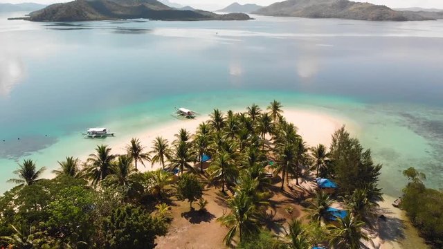 Aerial drone shot towards the ocean, over Paraw boats, anchored at a tropical, paradise isle, in turquoise sea, at Pass island, in Philippines, Asia