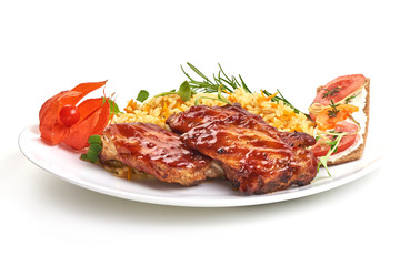 Delicious grilled pork ribs in BBQ sauce with pilaf on white plate, isolated on white background. Close-up.