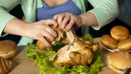 Overweight woman tearing pieces of roast chicken, overeating problem, stress