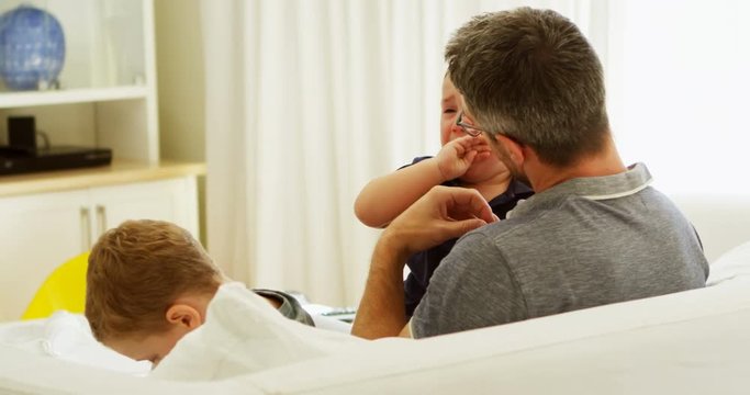 Father consoling his crying baby on sofa 4k