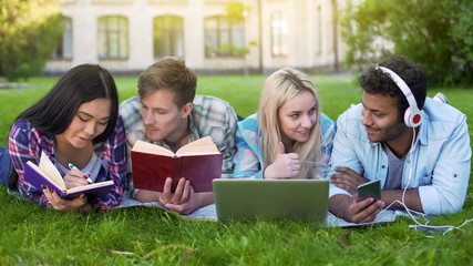 Group of students lying on grass, preparing for final exam, university education